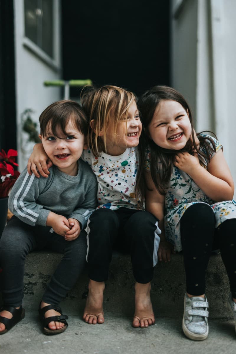 Drei lachende Kinder – Familienabsicherung in Österreich